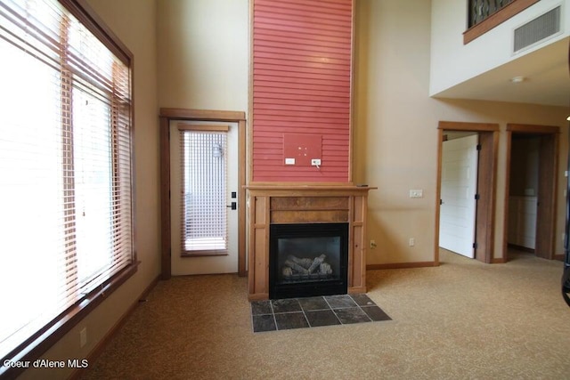 unfurnished living room featuring plenty of natural light and dark carpet