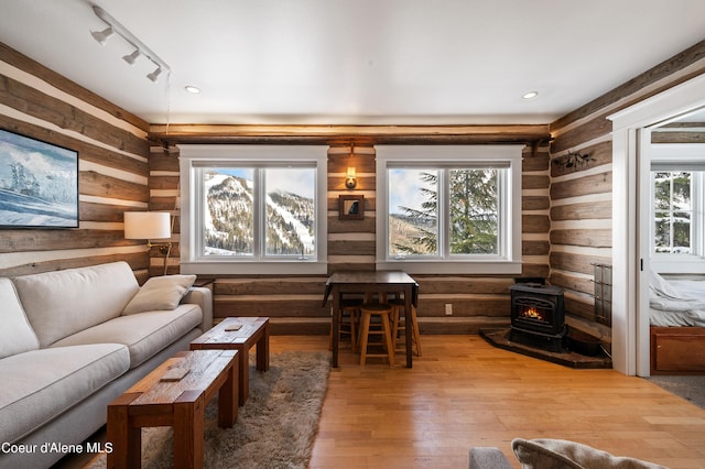 living room with hardwood / wood-style flooring, a wood stove, track lighting, and log walls