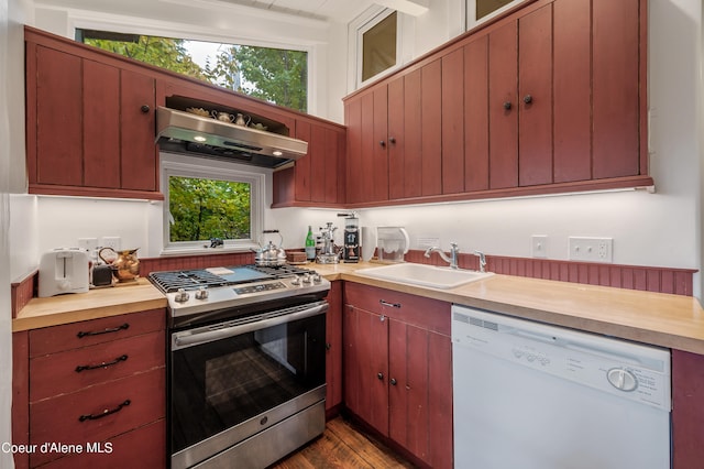 kitchen with dark hardwood / wood-style flooring, fume extractor, stainless steel range with gas cooktop, white dishwasher, and sink