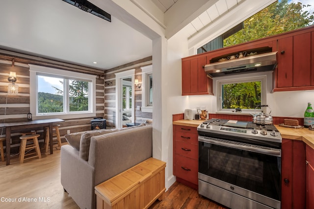 kitchen with vaulted ceiling with beams, hardwood / wood-style floors, gas stove, extractor fan, and log walls