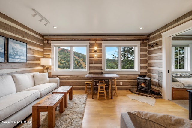 living room featuring hardwood / wood-style floors, track lighting, rustic walls, and a wood stove