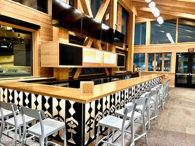 interior space featuring hanging light fixtures, butcher block counters, a high ceiling, and carpet floors