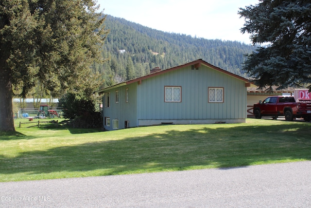 view of side of property with a mountain view and a yard