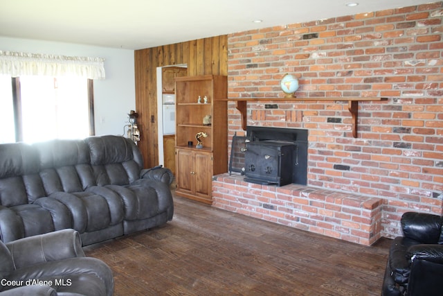 living room with dark hardwood / wood-style floors, a wood stove, and wooden walls