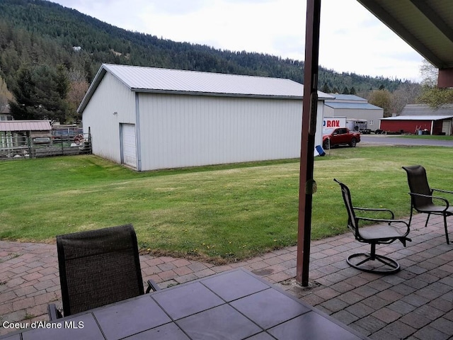 view of patio / terrace featuring a mountain view, an outdoor structure, and a garage