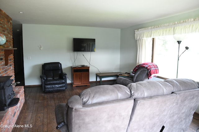 living room with wood-type flooring, a wood stove, and brick wall