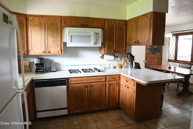 kitchen featuring kitchen peninsula, dark tile floors, and white appliances