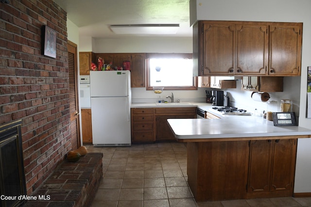 kitchen featuring tile flooring, sink, white appliances, brick wall, and kitchen peninsula