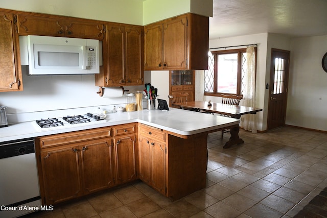 kitchen with kitchen peninsula, dark tile floors, and white appliances