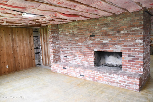 basement with brick wall, wood walls, and a fireplace