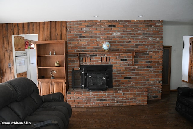 living room with a fireplace, dark hardwood / wood-style flooring, brick wall, and wooden walls