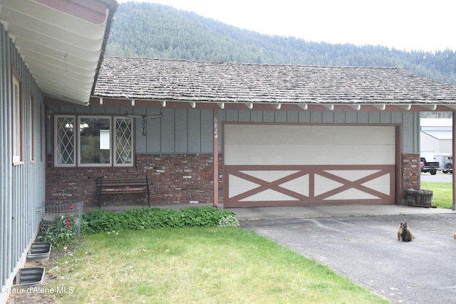 exterior space featuring a garage, a mountain view, and a yard