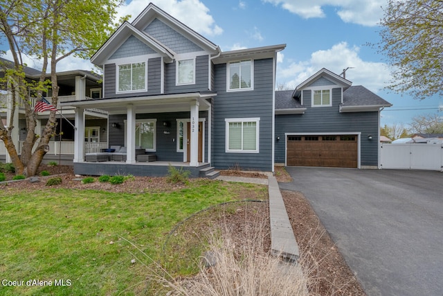 view of front of property with a garage, covered porch, and a front yard