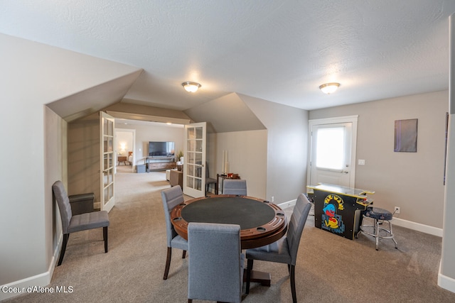 dining area with a textured ceiling, carpet, lofted ceiling, and french doors