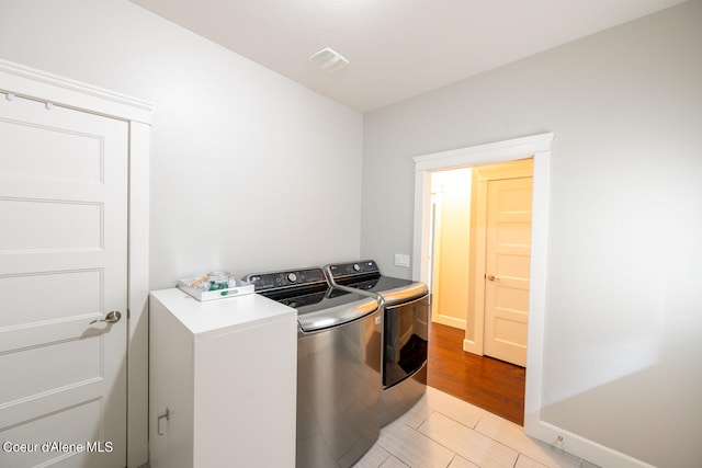 clothes washing area with light wood-type flooring and washer and clothes dryer