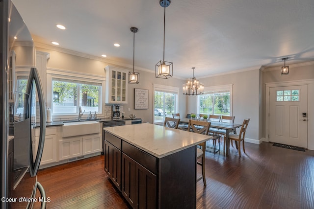 kitchen featuring a center island, decorative light fixtures, black fridge, dark wood-type flooring, and sink