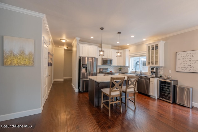 kitchen featuring appliances with stainless steel finishes, a center island, backsplash, white cabinetry, and dark wood-type flooring