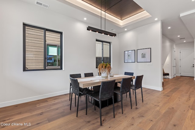 dining space featuring a tray ceiling and light hardwood / wood-style flooring