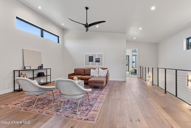 living room featuring light hardwood / wood-style floors, ceiling fan, and high vaulted ceiling