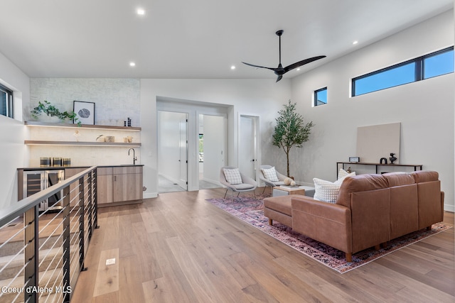 living room featuring ceiling fan, light hardwood / wood-style flooring, high vaulted ceiling, and a wealth of natural light