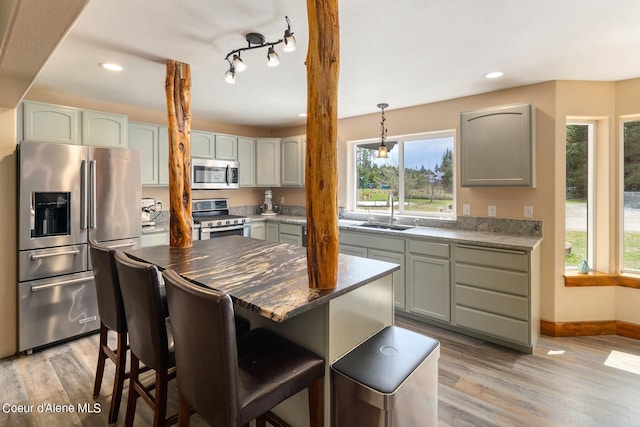 kitchen featuring appliances with stainless steel finishes, sink, light hardwood / wood-style floors, and a center island