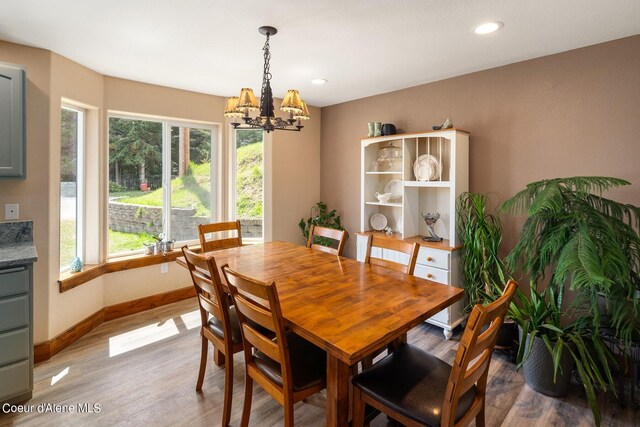 dining room with a wealth of natural light, dark hardwood / wood-style floors, and an inviting chandelier