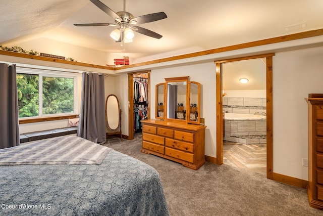 bedroom featuring a closet, ensuite bath, a spacious closet, a raised ceiling, and ceiling fan