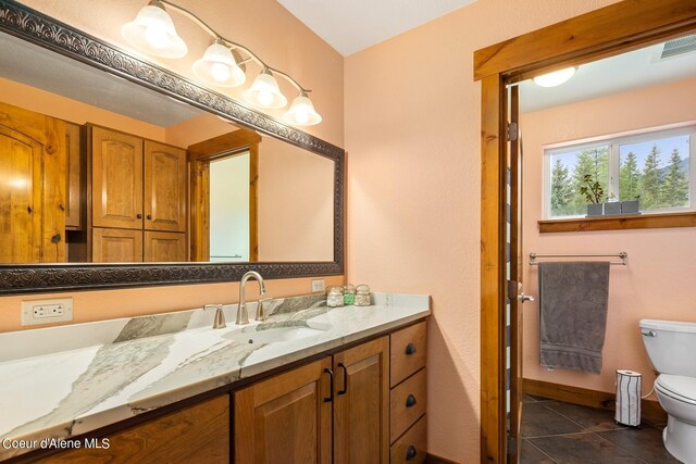 bathroom with vanity with extensive cabinet space, toilet, and tile flooring