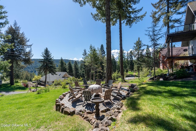 view of yard featuring a balcony, a patio area, and a fire pit