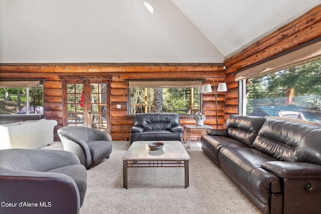 carpeted living room featuring plenty of natural light, high vaulted ceiling, and rustic walls