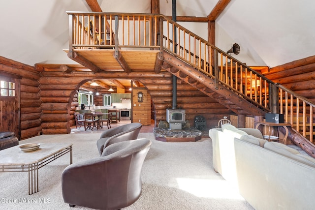 carpeted living room featuring log walls, high vaulted ceiling, a wood stove, and beamed ceiling