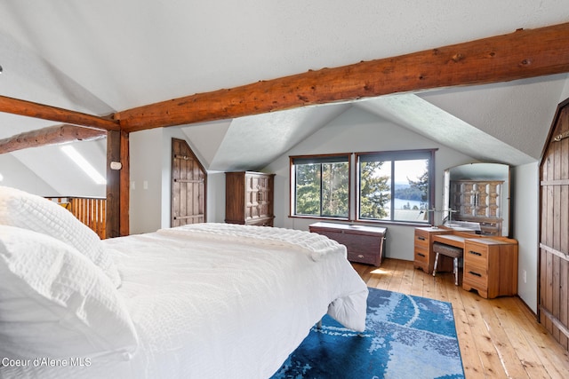 bedroom featuring lofted ceiling with beams, a textured ceiling, and light wood-type flooring