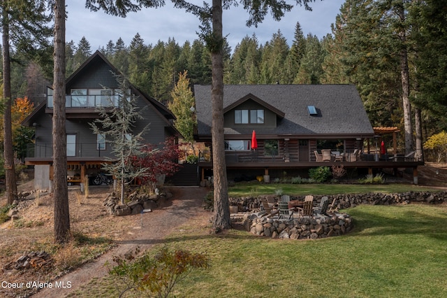 rear view of house featuring a yard, a patio area, a wooden deck, and a fire pit