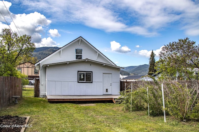 back of property with a mountain view and a yard