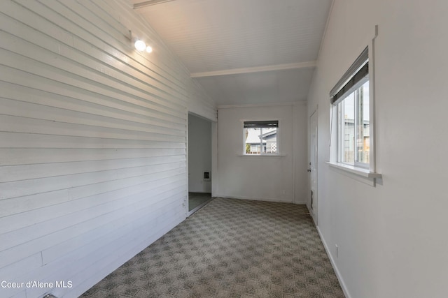 carpeted empty room with vaulted ceiling