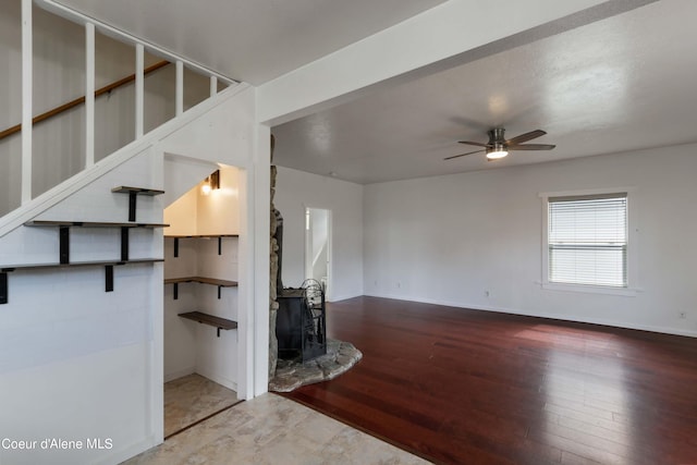 interior space with hardwood / wood-style floors, a wood stove, and ceiling fan