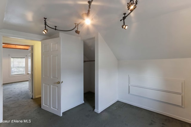 bonus room with dark carpet and vaulted ceiling