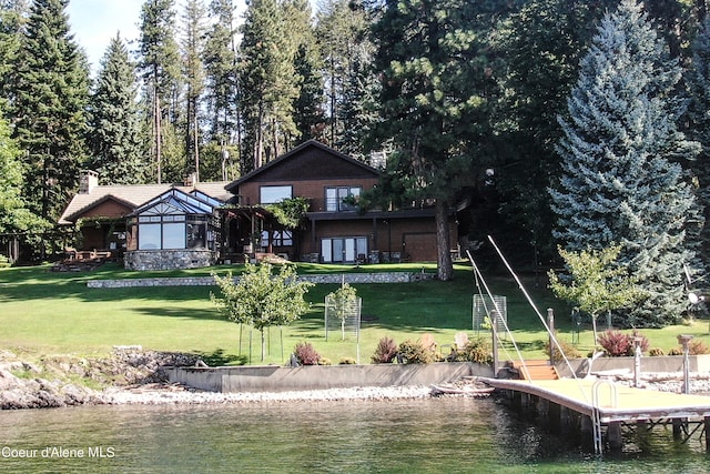 back of property with a water view and a yard