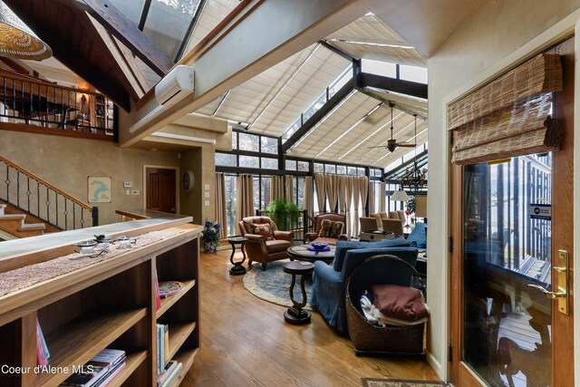 living room featuring a wall unit AC, beamed ceiling, hardwood / wood-style floors, high vaulted ceiling, and ceiling fan