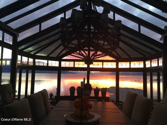 dining room with vaulted ceiling and a water view
