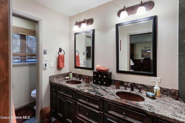 bathroom featuring dual bowl vanity and toilet