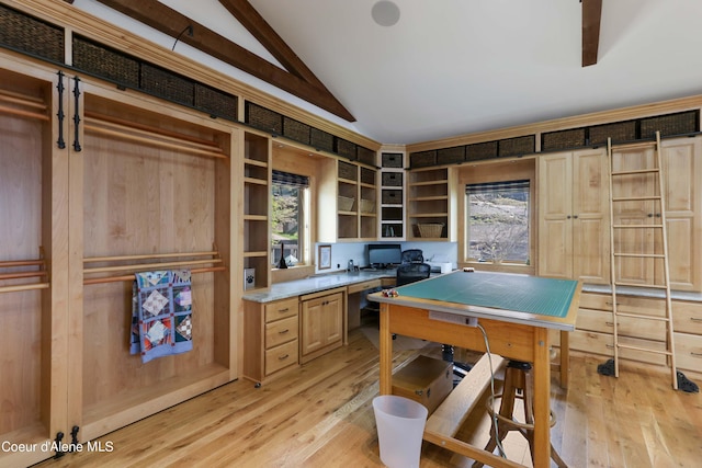 kitchen featuring built in desk, lofted ceiling with beams, light wood-type flooring, and light brown cabinets