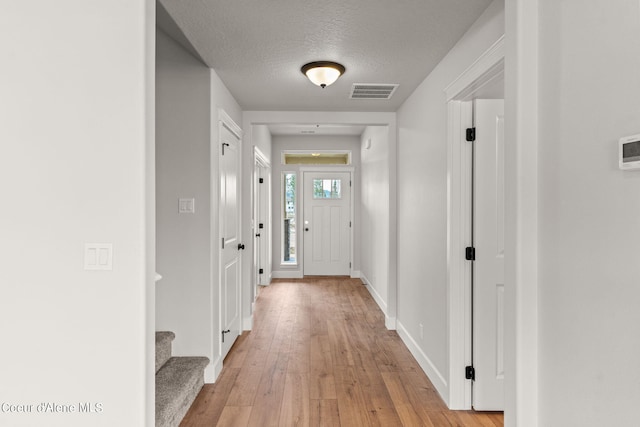 hallway with light hardwood / wood-style floors and a textured ceiling