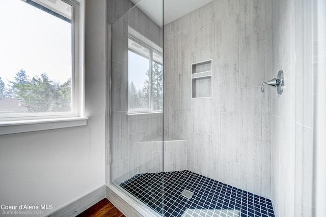 bathroom with tiled shower, a healthy amount of sunlight, and hardwood / wood-style floors