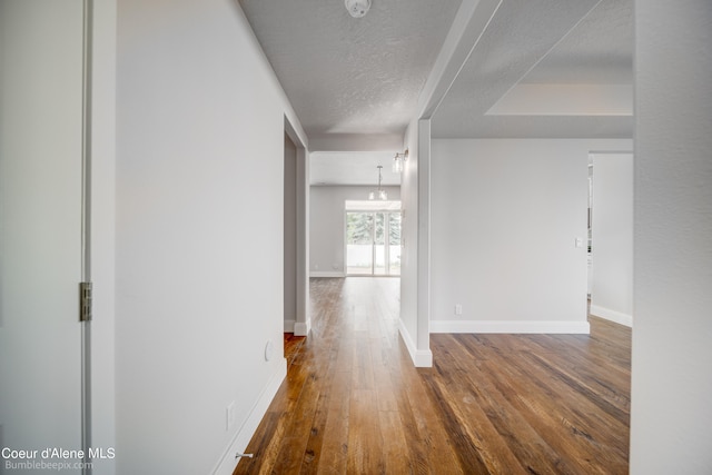 corridor featuring a textured ceiling and dark wood-type flooring