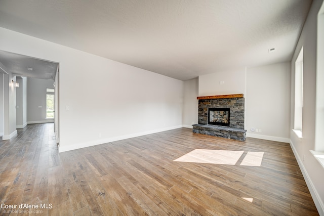 unfurnished living room with a stone fireplace and wood-type flooring