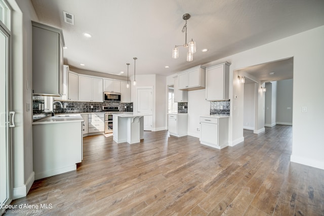 kitchen featuring wood-type flooring, hanging light fixtures, a center island, and a kitchen breakfast bar