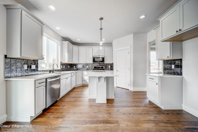 kitchen with stainless steel appliances, tasteful backsplash, a kitchen island, and wood-type flooring