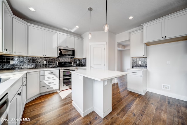 kitchen featuring a center island, dark wood-type flooring, range with two ovens, decorative light fixtures, and backsplash