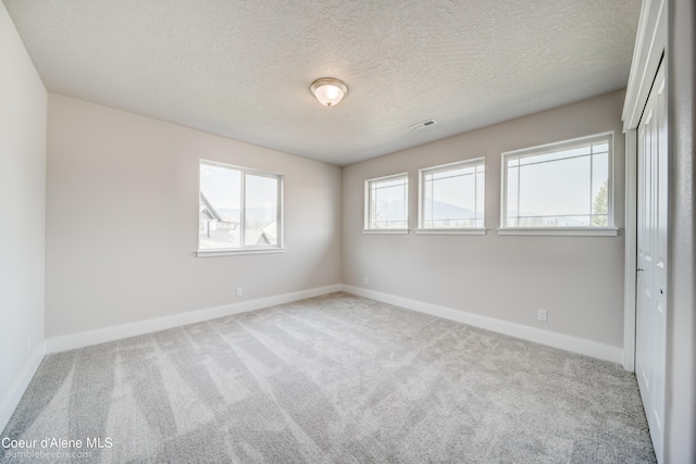 carpeted empty room with a textured ceiling